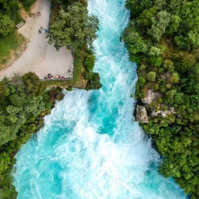Aerial view of a turquoise river surrounded by lush green forest and a small viewing platform.